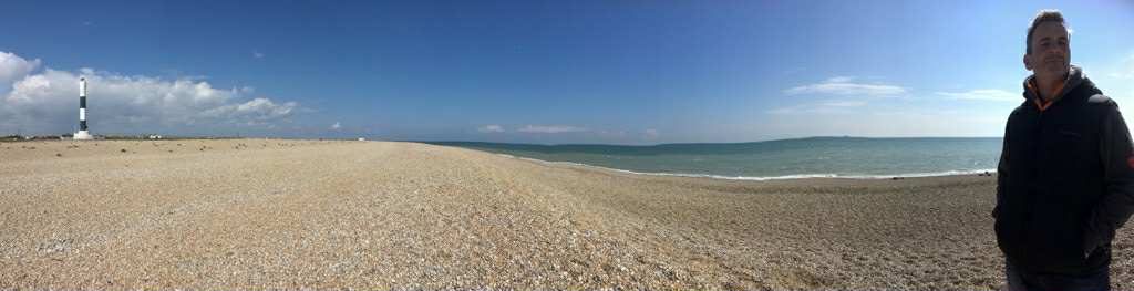 Wide panoramic view of Dungeness shingle beach and big sky